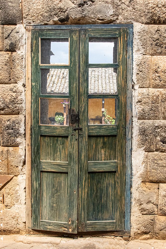 Old wooden door with worn out green paint between walls built by the Inca in the 1440s in Ecuador.